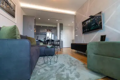 a living room with two blue couches and a table at Apartments Royal - Sakura Park in Novi Beograd