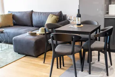 a table and chairs with a bottle of wine and a couch at Apartments Royal - Sakura Park in Novi Beograd