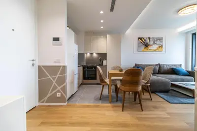 a living room and kitchen with a table and chairs at Apartments Royal - Sakura Park in Novi Beograd