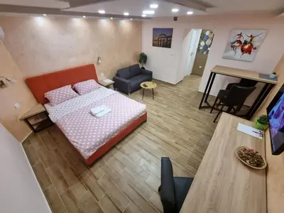 a room with a bed and a living room with a table at Apartman DoDoLuLu in Belgrade