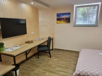 a room with a desk with a television and a bed at Apartman DoDoLuLu in Belgrade