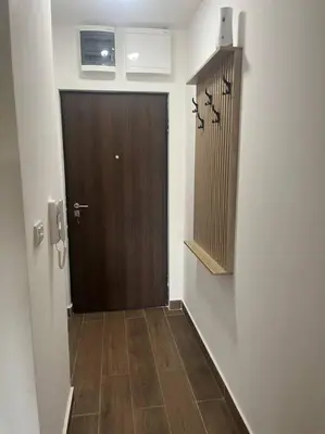 a hallway with a brown door and a wooden floor at Apartment SIA in Voždovac