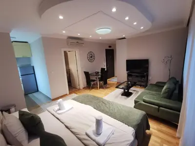 a living room with a green couch and a television at Fortuna Lux in Zvezdara