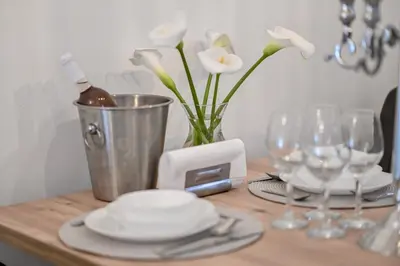 a table with glasses and a vase with white flowers at Porto lux in Arandjelovac
