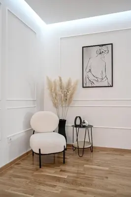 a white living room with a chair and a table at Porto lux in Arandjelovac