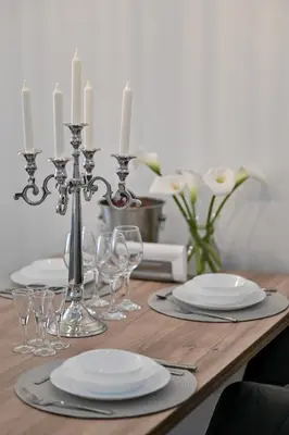 a wooden table with plates and wine glasses and candles at Porto lux in Arandjelovac