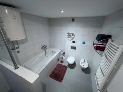 a white bathroom with a tub and a toilet at Owl Apartment in Belgrade