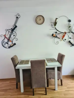 a dining room table with chairs and a clock on the wall at Friend LUX Apartman Beograd in Belgrade