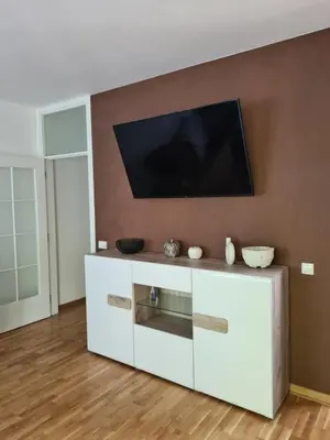 a white entertainment center with a flat screen tv on a wall at Friend LUX Apartman Beograd in Belgrade