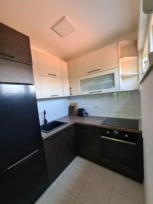 a kitchen with wooden cabinets and a black refrigerator at Friend LUX Apartman Beograd in Belgrade