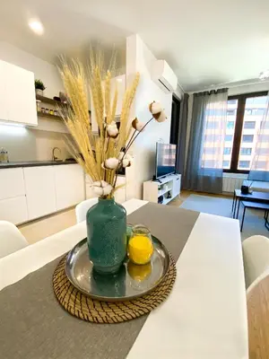 a green vase with flowers and two lemons on a table at Belgrade Riverfront Fortress Apartment in Belgrade