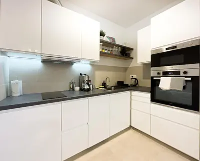 a white kitchen with white cabinets and black appliances at Belgrade Riverfront Fortress Apartment in Belgrade