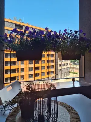 a table with flowers on a balcony with a window at Belgrade Riverfront Fortress Apartment in Belgrade