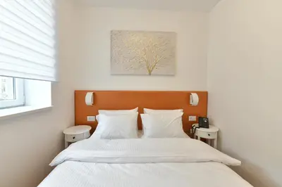 a bedroom with a bed with white sheets and a tree painting at Royal Wellness and Spa in Ruma