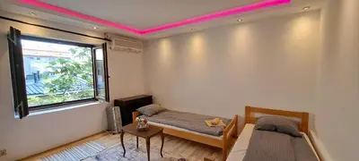 a room with two beds and a window with pink lighting at Quiet place near the city center in Sajmište