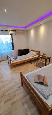 two beds in a room with purple lighting at Quiet place near the city center in Sajmište