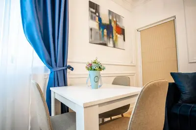 a white table with a vase of flowers on it at Apartman Provance in Batajnica