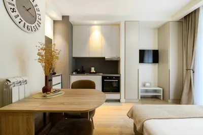 a kitchen and living room with a wooden table in a room at inJoy in Belgrade