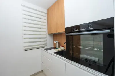 a kitchen with a black microwave and white cabinets at Comanda LUXURY APARTMENTS in Belgrade