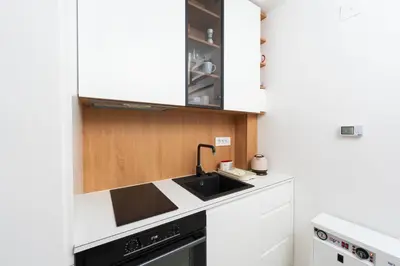 a kitchen with white cabinets and a black sink at Comanda LUXURY APARTMENTS in Belgrade