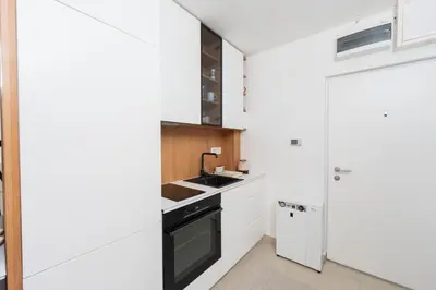 a kitchen with white cabinets and a black stove top oven at Comanda LUXURY APARTMENTS in Belgrade