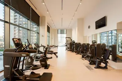 a gym with rows of treadmills and elliptical machines at Queen BW in Sajmište