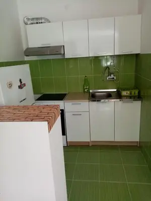 a kitchen with white cabinets and green tiles at Martin in Belgrade