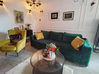 a living room with a green couch and a table at Maximilian apartman in Smederevo