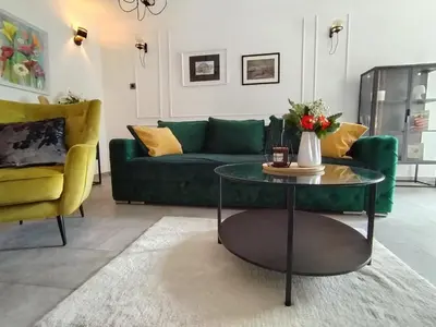 a living room with a green couch and a table at Maximilian apartman in Smederevo