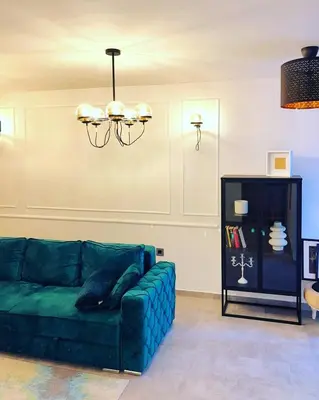 a living room with a green couch and a chandelier at Maximilian apartman in Smederevo