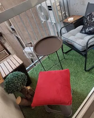 a small balcony with a table and a chair and a green rug at Maximilian apartman in Smederevo