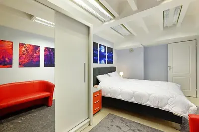 a bedroom with a white bed and a red couch at Apartman Tara in Belgrade
