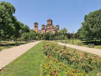 a park with a building in the background with flowers at Apartman Tara in Belgrade