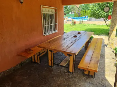 a wooden table and two benches against a wall at Vila Tea Fruska Gora in Čortanovci
