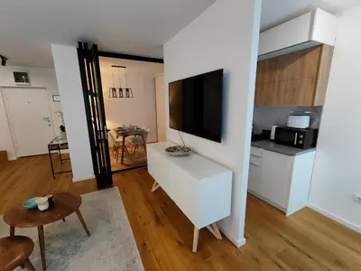 a living room with a tv and a white kitchen at Elixir in Belgrade