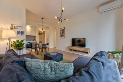 a living room with a couch and a living room with a table at ZIGZAG Belgrade Waterfront Aqua in Belgrade