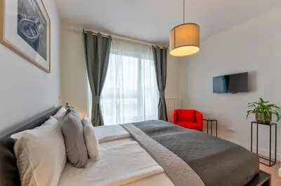 a bedroom with a bed with a window and a red chair at ZIGZAG Belgrade Waterfront Aqua in Belgrade