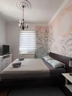 a bedroom with a bed and a flowery wall at Apartman Sasha 1 - Ask for free parking in Sajmište
