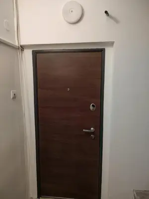 a wooden door in a room with a clock on the wall at Charna apartment Beograd Železnik in Železnik