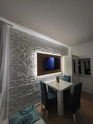a dining room with a table and a tv on a brick wall at HARMONY Suites (Savska ulica) in Sajmište