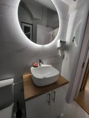 a bathroom with a white sink and a mirror at HARMONY Suites (Savska ulica) in Sajmište