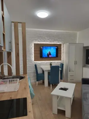 a living room with a table and a tv on a brick wall at HARMONY Suites (Savska ulica) in Sajmište
