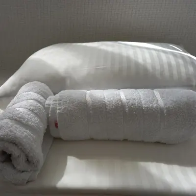 a stack of white towels sitting on a bed at RIVIJERA LAKES Ada Studio in Belgrade