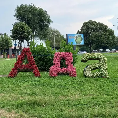 a sign for a park with flowers in the grass at RIVIJERA LAKES Ada Studio in Belgrade