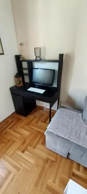 a room with a desk with a television and a wooden floor at RubiCon Apartments in Belgrade