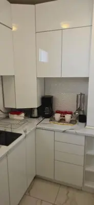 a kitchen with white cabinets and two bowls on a tray at Bella apartman in Mladenovac