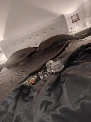 a bed with a black comforter and glasses on it at Bella apartman in Mladenovac