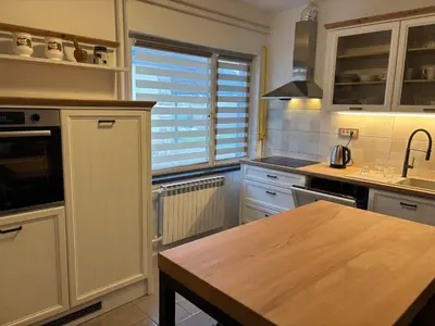 a kitchen with white cabinets and a wooden table at Apartman u potkrovlju in Sremski Karlovci