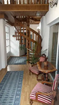 a room with a table and chairs and a wooden staircase at Apartman u potkrovlju in Sremski Karlovci