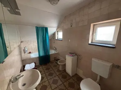 a bathroom with a sink and a toilet and a window at Apartman u potkrovlju in Sremski Karlovci